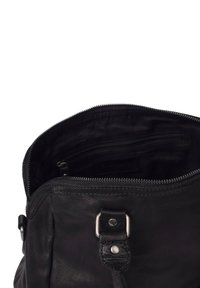 Bolso de cuero negro con apertura de cremallera, que presenta una textura suave y un grano sutil. En el interior hay un pequeño bolsillo con cremallera y una etiqueta de marca.