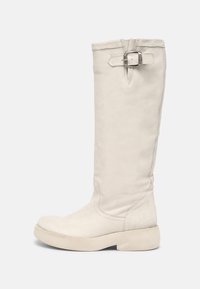 Bota de cuero blanca hasta la rodilla con un acabado texturizado, suela plana y un detalle de hebilla en la parte superior. Superficie lisa y puntera redondeada.