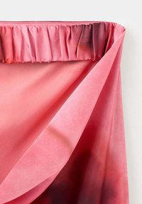Jupe en velours rose avec taille élastique froncée et un pli révélant l'envers du tissu sur fond blanc.