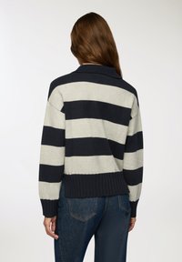 Sweter w paski w kolorze granatowym i jasnoszarym, z prążkowanym dołem i kołnierzem, luźnymi rękawami oraz swobodnym krojem, wykonany z miękkiego materiału dzianinowego.