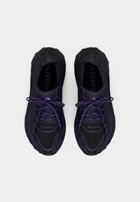 Paire de chaussures de course Gore-Tex noires et violet foncé avec lacets, vues de dessus sur un fond blanc.