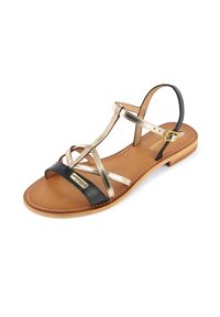 Sandale plate avec une sangle en cuir noire, des sangles avec des accents dorés et une semelle en cuir marron. Présente une fermeture à boucle et des détails cousus.