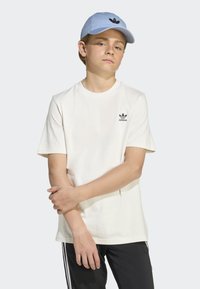 T-shirt en coton blanc à manches courtes avec un petit logo Adidas noir sur la poitrine, associé à une casquette de baseball bleu clair arborant le même logo.