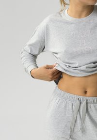 Szary bawełniany sweatshirt z długimi rękawami i napisem "TAKE IT EASY" w jasnoróżowym kolorze. Zestawiony z dopasowanymi szarymi spodnimi joggerami ze sznurkiem.