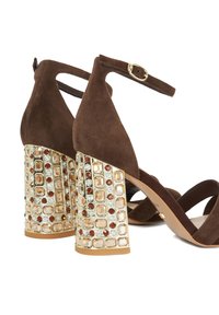Brown suede high-heeled sandals with a decorative embellished block heel featuring clear and amber gemstones set in a gold-toned base.