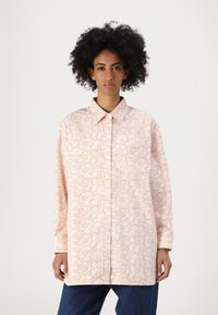 Camisa de manga larga en tejido rosa pastel con patrón de flores blancas y contornos naranjas, que presenta un cuello clásico y un bolsillo en el pecho.