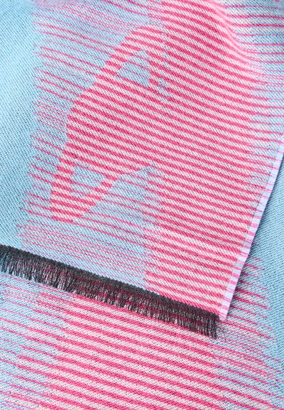 Tissu tricoté avec des rayures diagonales alternées roses et bleues et une frange noire le long d'un bord.