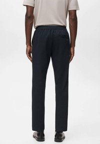 Donkerblauwe sweatpants met een elastische tailleband en een achterzak, gemaakt van zacht, geweven materiaal. De zijnaad is recht en goed gesneden.