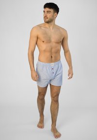 Boxer blu a righe realizzati in cotone, con un elastico in vita e tre bottoni rossi sul davanti. Tessuto semplice e morbido con una vestibilità comoda.