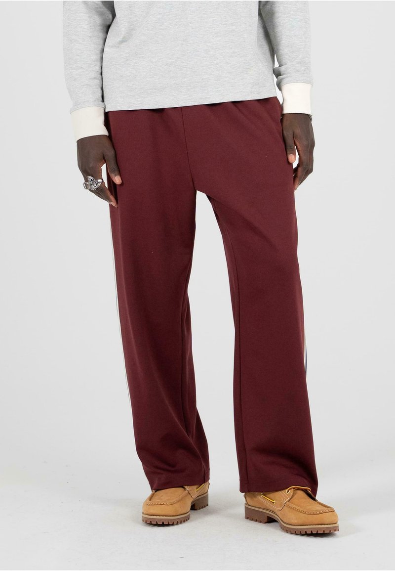 Bordové široké nohavice z jemnej látky s hladkým povrchom, skombinované s hnedou obuvou s chunky podrážkou a ozdobným šitím.