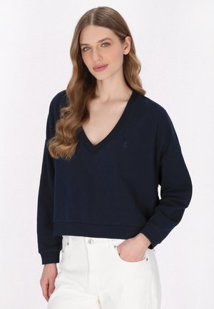 Felpa cropped blu navy con scollo a V, maniche lunghe e polsini a coste. Presenta un sottile logo dell'ancora sul petto.