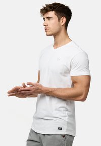 Hvid v-neck t-shirt lavet af blødt stof, med korte ærmer og et lille logo på brystet. Casual fit med lige kant.