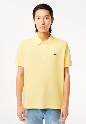 Polo giallo realizzato in cotone testurizzato, con colletto classico e maniche corte. Presenta un logo ricamato verde sul lato sinistro del petto.