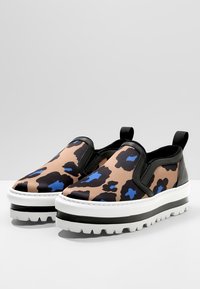 Sneakers typu slip-on z nadrukiem w panterkę w odcieniach brązu i czerni z niebieskimi akcentami, białą masywną podeszwą i czarnymi teksturowanymi bokami.