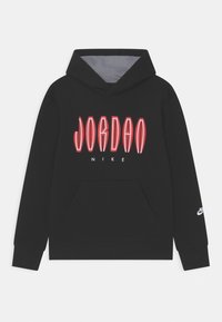 Felpa nera con cappuccio dotata di tasca a marsupio frontale, testo "JORDAN" contornato di rosso, piccolo "NIKE" bianco sotto, e logo bianco sulla manica sinistra.