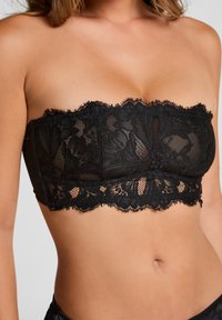 Zwarte kanten strapless bralette met bloemenpatronen, textuurstof en een golvende kantafwerking langs de onderrand.
