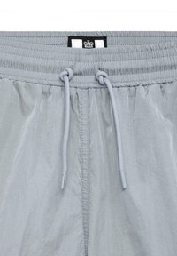 Lysegrå shorts med elastisk talje, justerbar snor og et lille sort mærke med et kongekrone-logo øverst.