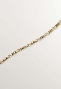 Pulsera de cadena de metal dorado con eslabones ovalados de diseño retorcido y acabado pulido, colocada plana sobre un fondo claro.