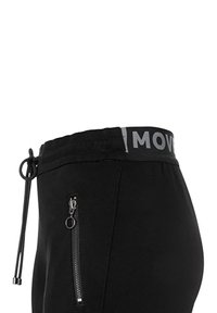 Joggers negros con cintura ajustable por cordón, cuentan con una banda en la cintura gris contrastante con el texto "MOVE" y un detalle de bolsillo lateral con cremallera.