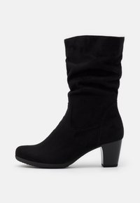 Bottines en suède noir avec un design lâche, bout rond et un talon empilé. Présente des accents cousus et une texture douce.