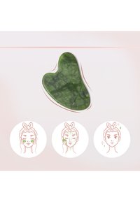 Grünes Jade-Gesichtsinstrument in Herzform mit glatter Oberfläche. Begleitet von Illustrationen, die Gesichtsmassage-Techniken darstellen.