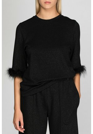 Black top with a soft, glittery texture, featuring 3/4 sleeves trimmed with black fur at the cuffs, worn over matching trousers.