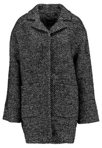 Cappotto oversize in bianco e nero, con texture, colletto, chiusura anteriore con bottoni e due tasche frontali. Presenta un motivo diagonale su tutta la superficie.