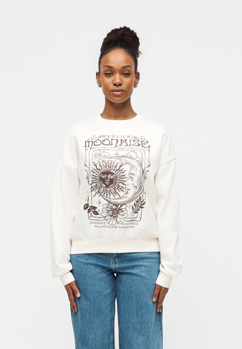 Φούτερ σε κρεμ απόχρωση με λεπτομερή καφέ γραφικό σχέδιο με ουράνια μοτίβα, συμπεριλαμβανομένου ήλιου και φεγγαριού, στρογγυλή λαιμόκοψη και ριμπ μανσέτες.