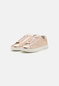 Rose gold sneakers made of metallic fabric with a smooth finish, featuring a white sole, lace-up design, and subtle perforated accents.