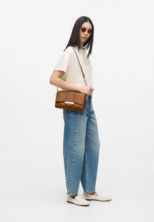 Pruun nahast ristkere kott klappkinnitusega, hõbedase metallrõngaga ja tekstureeritud pinnaga. Sobitatuna helesiniste kõrge vöökohaga teksade ja beežide kingadega.