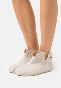 Felt ankle boots in light gray with brown leather accents, featuring a rounded toe and side cutouts for easy wear. Rubber soles visible.