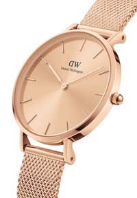 Rožu zelta acu siksna pulkstenis ar minimālistisku apaļu seju, kurā ir plāni stundu rādītāji un rokas, apzīmēts ar "Daniel Wellington."