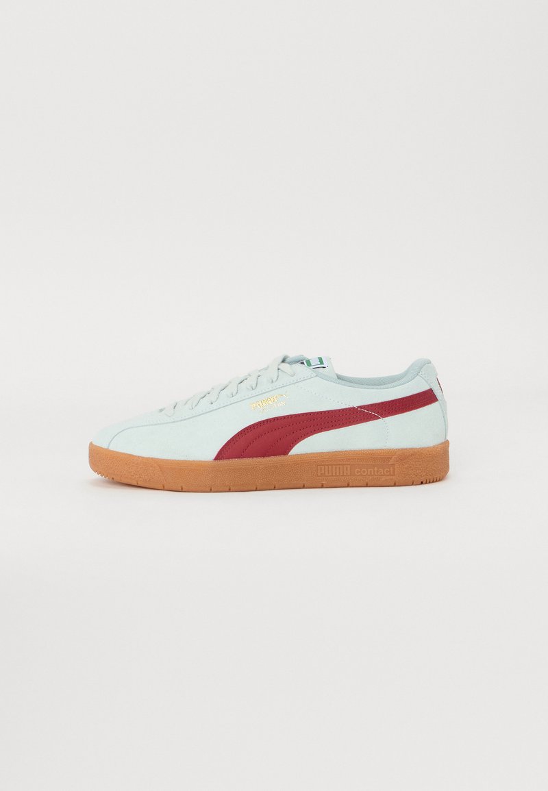 Lys blå semsket sneakers med røde detaljer, brun gummisåle, snøringsdesign og gulllogo dekoring på siden og tungen.