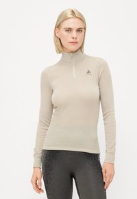 Long-sleeve, high-collar shirt in light beige, featuring a half zipper and textured fabric. Brand logo on the chest, slim fit design.