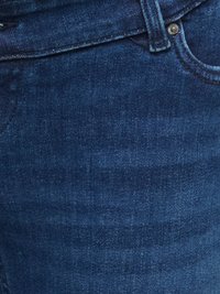 Gros plan sur un jean en denim bleu foncé montrant la poche, la boucle de ceinture, les coutures et les rivets métalliques.