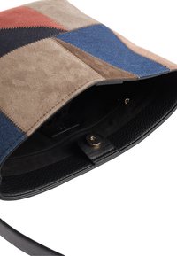 Patchwork-Handtasche aus Wildleder und Leder in verschiedenen Brauntönen, Blau und Rot; das Innere hat ein schwarzes Futter und eine Reißverschlusstasche.