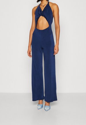 Mørkeblå halterneck jumpsuit med en snoet front og en sideskæring. Lavet af glat stof, med brede ben og en tætsiddende overdel.