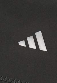 Sort stof med en glat tekstur præsenterer et hvidt logo design med tre stænger i forskellige størrelser, placeret i en diagonal formation.