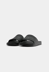 Sorte sorte sandaler i svart, laget av glatt materiale, med åpen tå-design og en fremtredende logo på stroppen. Flat såle med teksturert grep.