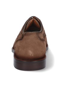 Mocasines de ante marrón con puntera redondeada, tacón de madera marrón oscuro y un sencillo detalle de costura a lo largo de los lados. Forro interior suave.