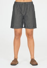 Grå knälånga shorts med elastisk midja och dragsnöre. Har två framfickor och uppvikta mudd. Bärs med bruna slip-in-skor.