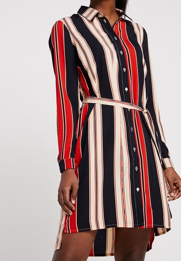 Femme portant une robe-chemise ceinturée à manches longues avec des rayures verticales rouges, noires et beiges, et une fermeture à boutons sur le devant.