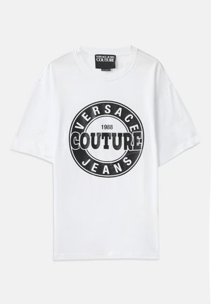 Hvid bomuld t-shirt med et fremtrædende sort cirkulært grafisk motiv med teksten "VERSACE JEANS COUTURE 1988" i fed skrift. Korte ærmer.