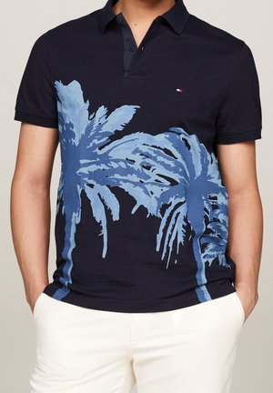 Granatowa koszulka polo z bawełny z nadrukiem sylwetkowym jasnoniebieskich palm, z kołnierzykiem na guziki i krótkimi rękawami, w połączeniu z białymi spodniami.