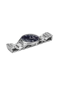 Reloj de metal plateado con un dial redondo de color azul marino, agujas plateadas, indicador de fecha y pulsera de eslabones de acero inoxidable. Acabado suave y acentos pulidos.