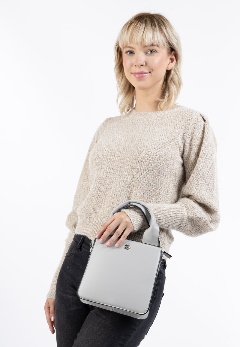Borsa quadrata grigia realizzata in pelle liscia con un design strutturato, manici corti e un'emblema in metallo sulla parte anteriore.