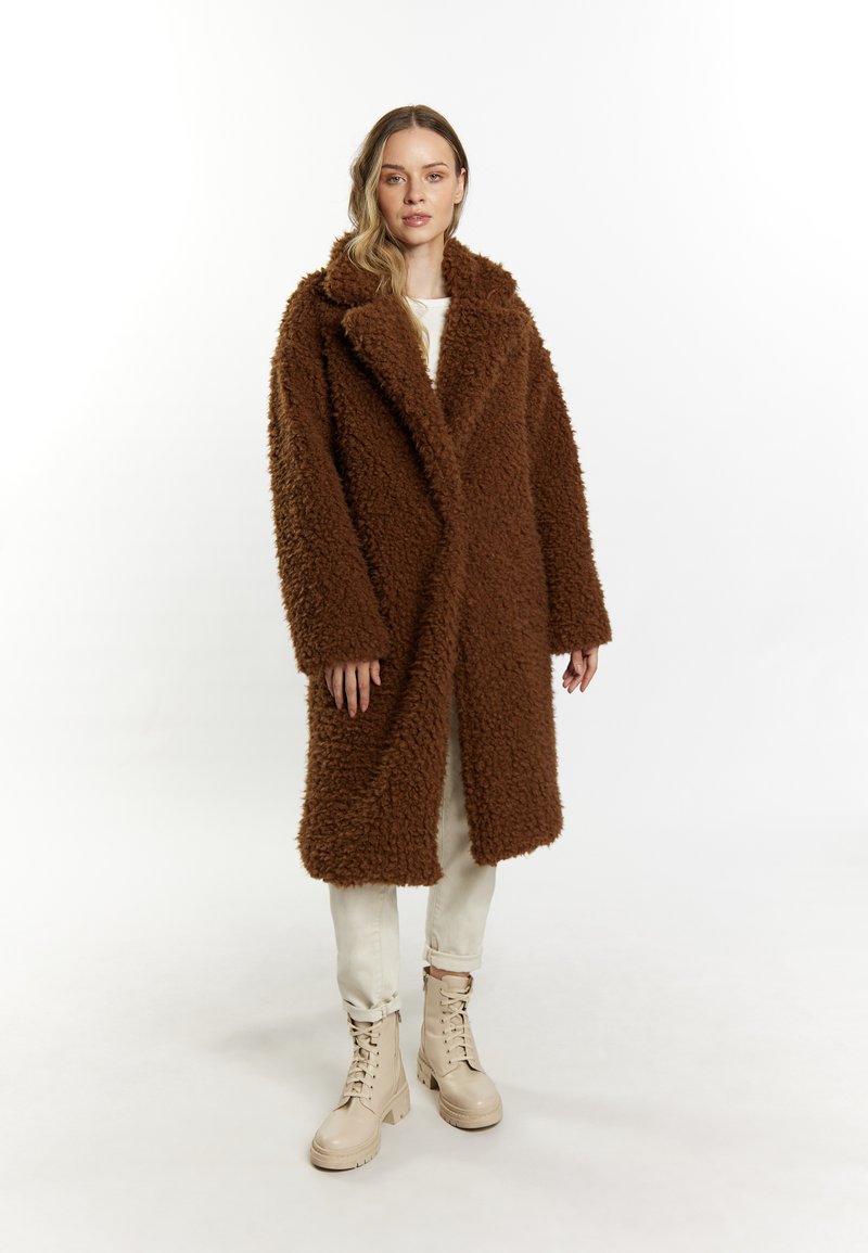 Brun fluffy oversized frakke med kilekrave, to frontlommer og en afslappet silhuet, parret med lysebeige combat støvler.
