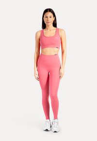 Roze sportbeha en legging gemaakt van rekbare, vocht afvoerende stof, met een naadloos ontwerp en minimale logo-accenten.