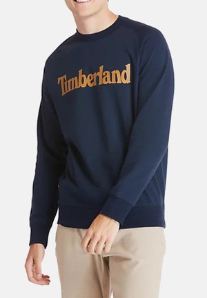 Marineblaues Sweatshirt mit goldenem "Timberland" Schriftzug. Ausgestattet mit langen Ärmeln sowie gerippten Bündchen und Saum. Weicher Stoff mit klassischer Passform.