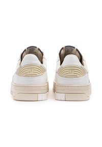 Sneaker bianche in pelle con tacco testurizzato e suola crema. La parte posteriore presenta dettagli del logo impresso e una cucitura.